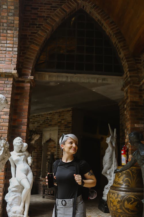 Smiling Woman Standing with Sculptures near