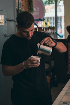 Focused barista creating latte art in a cozy cafe environment.