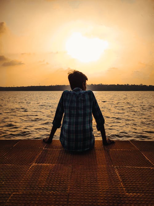 Sun Setting over a Person Sitting Alone at the Coast