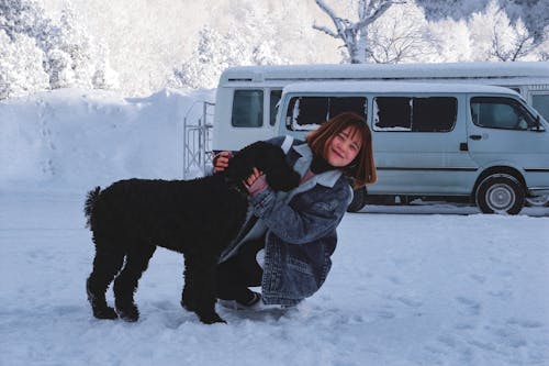 ショートコートの黒い犬を抱き締める女性