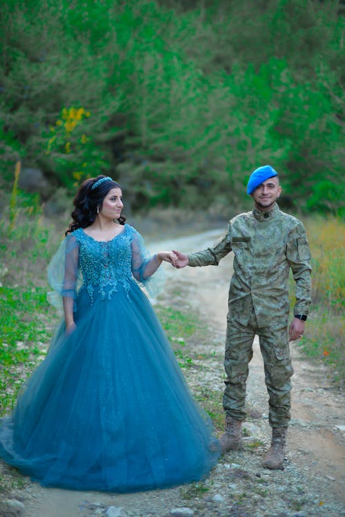 Woman in a Blue Dress and Man in a Military Uniform Holding Hands 