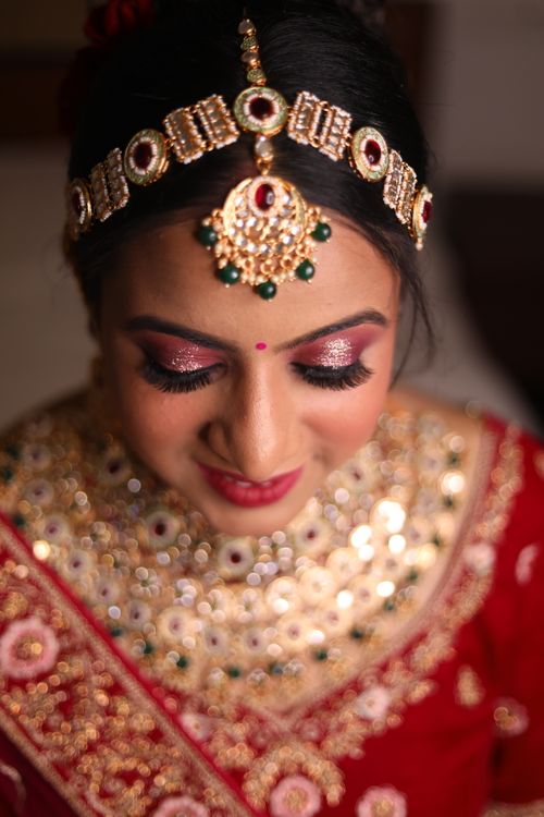 Free Close-up portrait of a smiling Indian bride in traditional red and gold wedding attire. Stock Photo