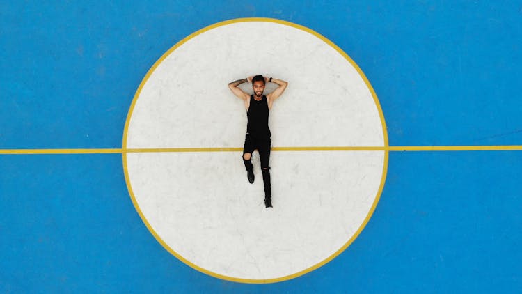 Top View Of A Man Lying In The Middle Of A Basketball Court