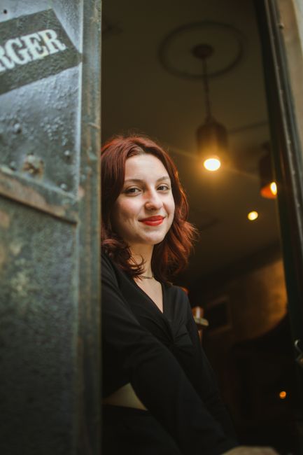 Portrait of a smiling woman with red hair posing indoors at a café in İstanbul, Türkiye.