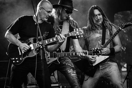 Free Group of Men Playing Guitar in Concert in Grayscale Photo Stock Photo
