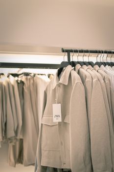 Stylish beige coats neatly arranged on racks in a modern clothing store interior.