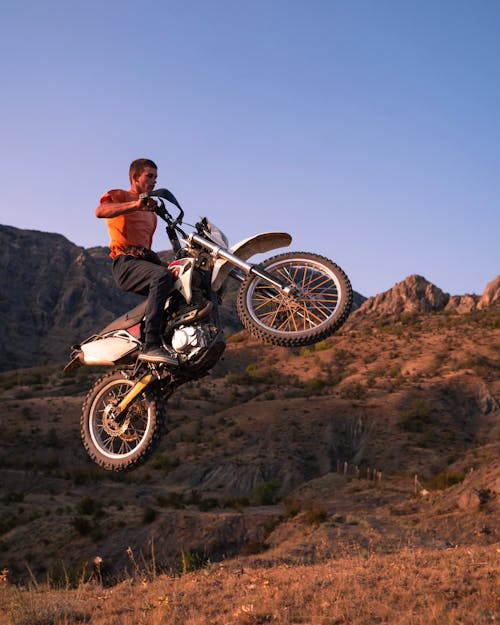 Man Jumping on Motorcycle in Mountains Landscape