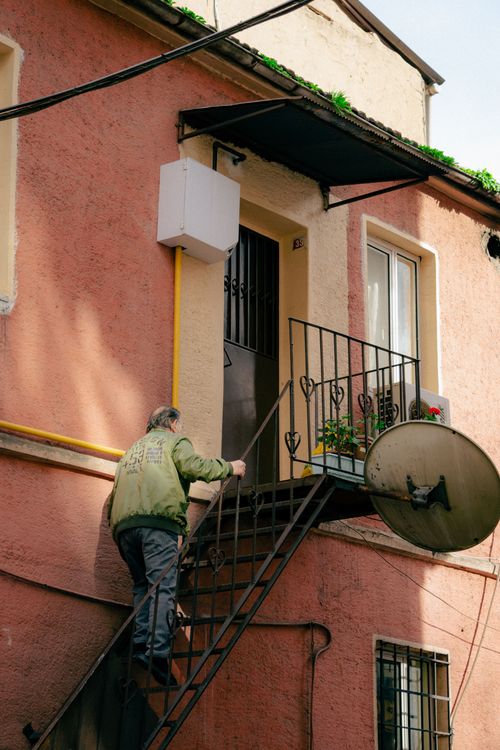 Free A senior man climbs exterior stairs to a residential urban home, emphasizing independent living. Stock Photo