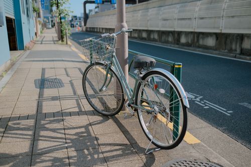 Free A bicycle with a basket parked on a sunlit sidewalk in Tokyo, Japan. Stock Photo