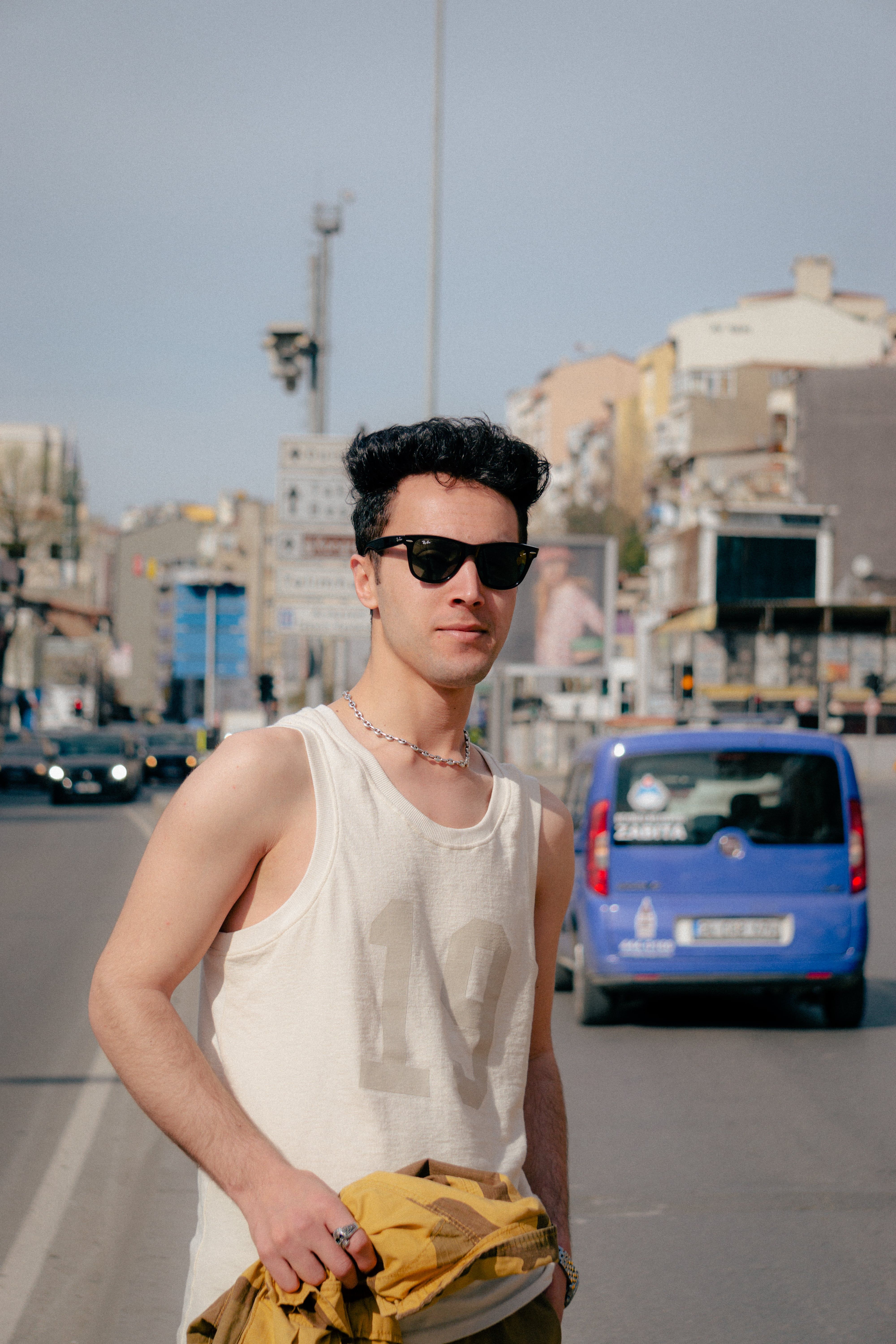 Young man in sunglasses on a city street, exuding casual summer vibes.