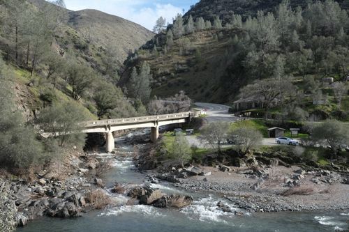 Free A picturesque bridge crossing a river in a rural, hilly landscape. Stock Photo