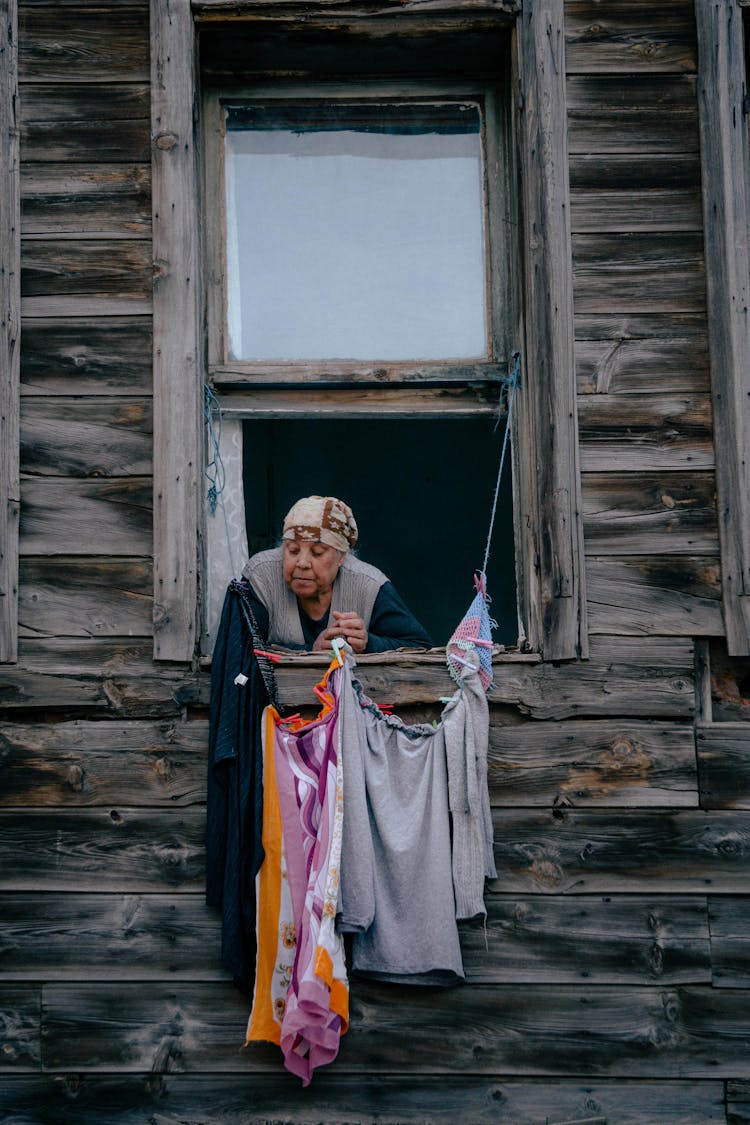 Woman In Window With Drying Clothes Below