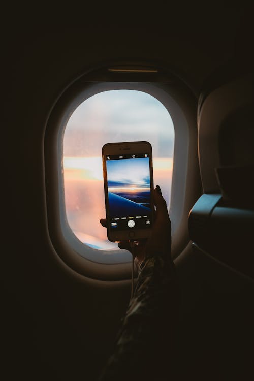 Free Person Holding Smartphone Inside Airplane Stock Photo
