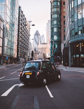伦敦街道上，经典的黑色出租车在标志性摩天大楼的背景下行驶