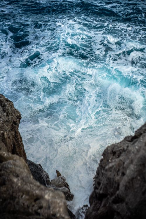 Free A powerful view of ocean waves crashing against the rugged coastline cliffs. Stock Photo