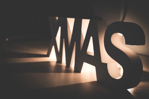 Free Creative close-up of lighted Xmas letters casting shadows in a warm, cozy atmosphere. Stock Photo