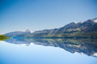 平静的湖面倒映着令人惊叹的山峦，在澄澈的蓝天下，尽显自然之美