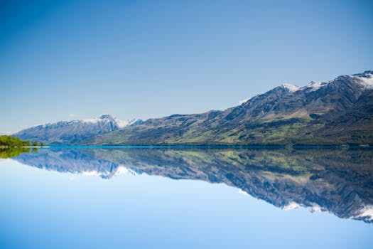 平静的湖面倒映着令人惊叹的山峦，在澄澈的蓝天下，尽显自然之美