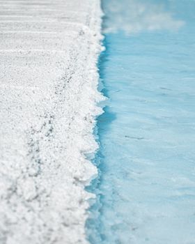 A stunning close-up of a salt shoreline meeting a vibrant blue lake, showcasing natural beauty and contrast.
