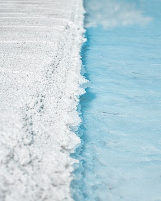 A stunning close-up of a salt shoreline meeting a vibrant blue lake, showcasing natural beauty and contrast.