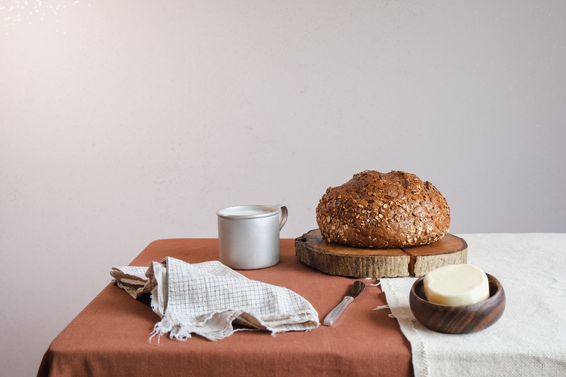 Artistic display of whole grain bread with butter and cloth napkin on a table.