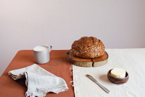 Free A cozy breakfast setup featuring rustic bread, butter, and milk on a wooden table. Stock Photo