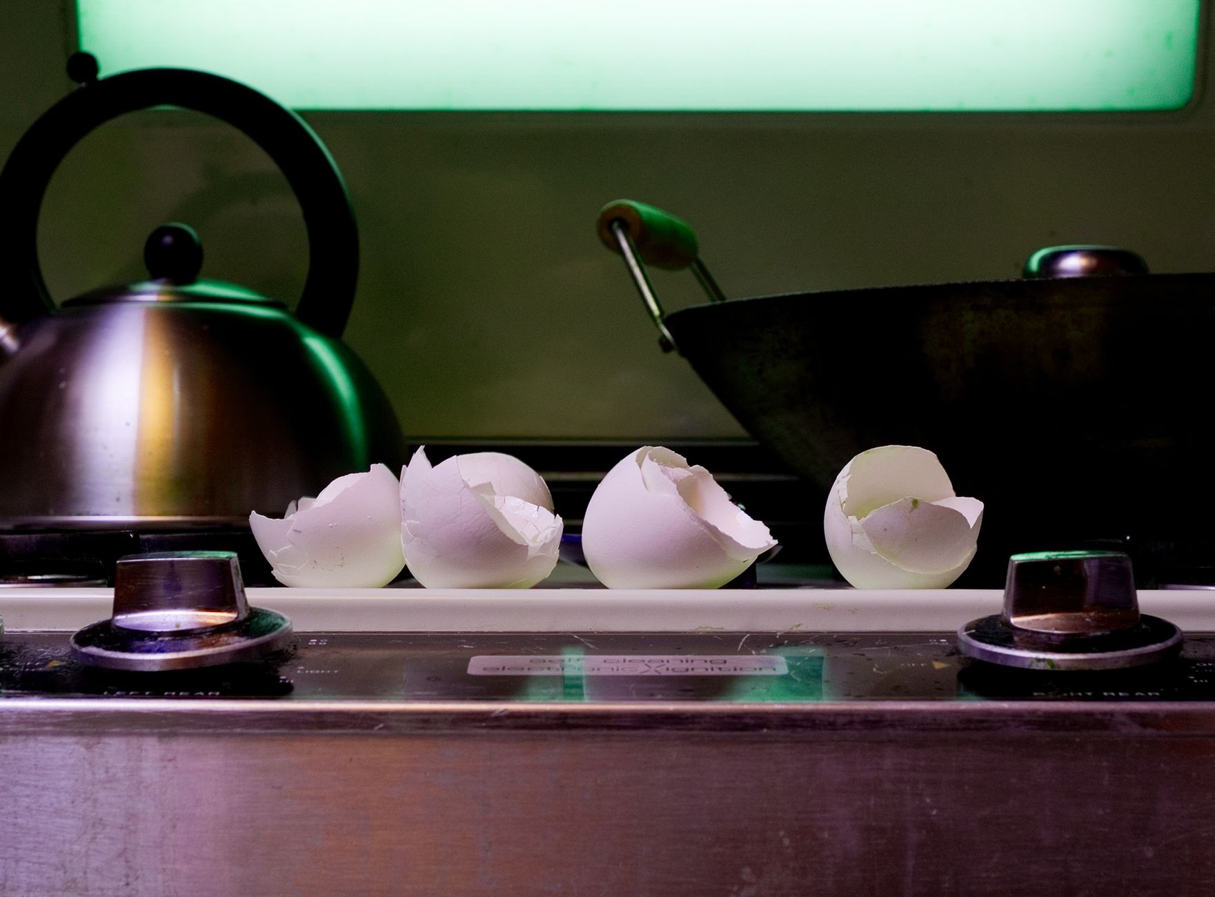 Artistic shot of eggshells on a stove in a modern kitchen setting.