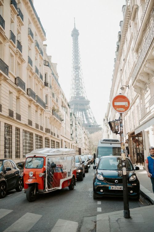 Free A bustling Parisian street with the Eiffel Tower in the background, showcasing urban life. Stock Photo