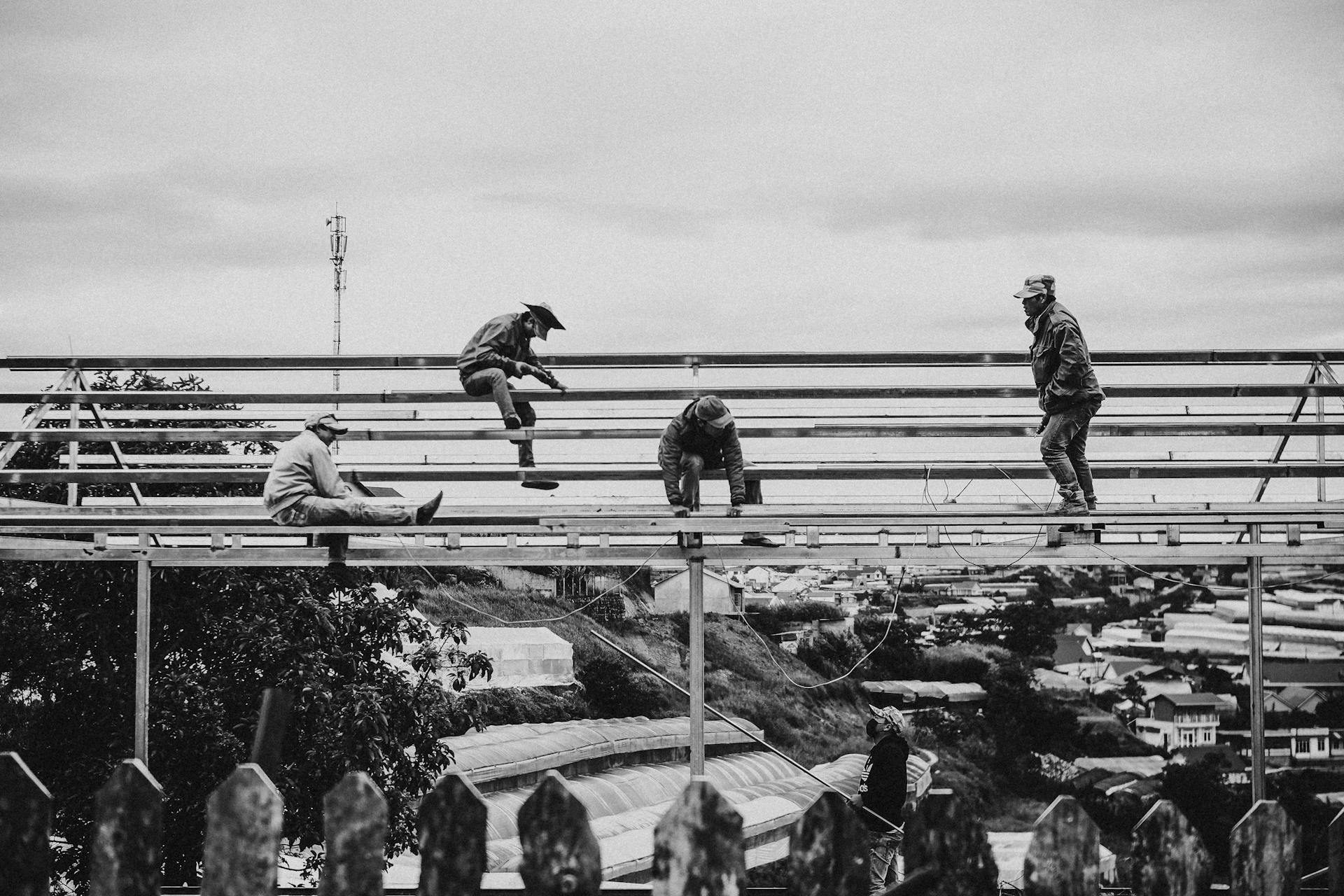 Grayscale Photo of Men Working on a Scaffolding