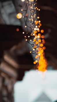 Close-up shot of warm-colored hanging Christmas lights with beautiful bokeh effect, perfect for holiday themes.