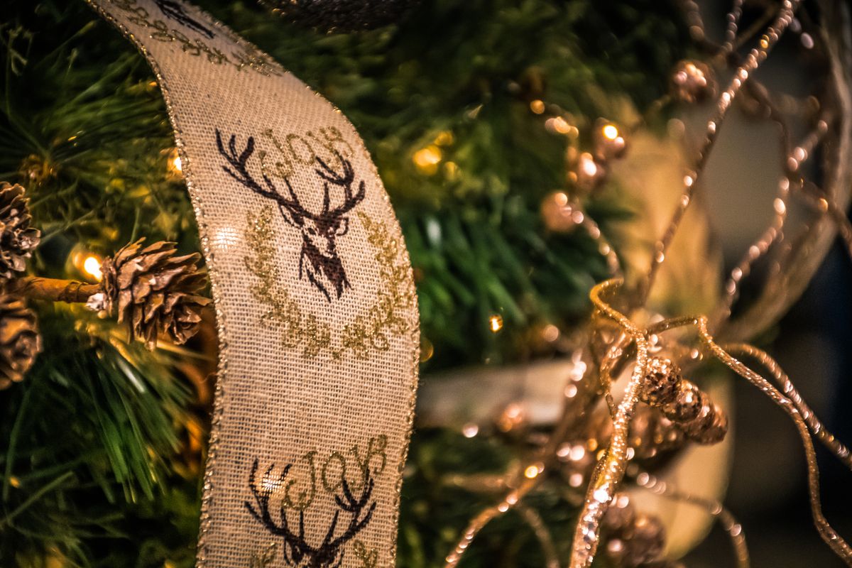 Christmas tree decorations with ribbons, lights, and pinecones close-up