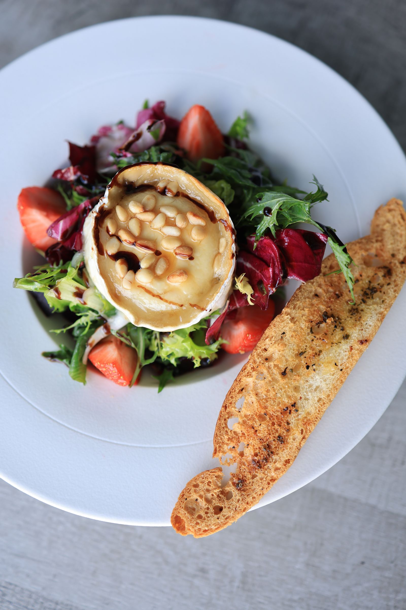 Gebakken camembert met brood en garnituur.
