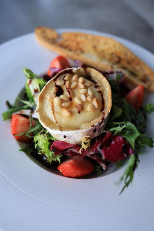 Free Close-up of a gourmet salad featuring cheese, strawberries, and pine nuts, perfect for a healthy lunch. Stock Photo