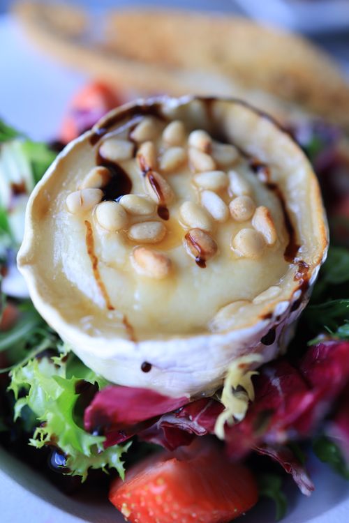 Free Close-up of baked camembert cheese on a fresh salad with mixed greens and strawberries. Stock Photo