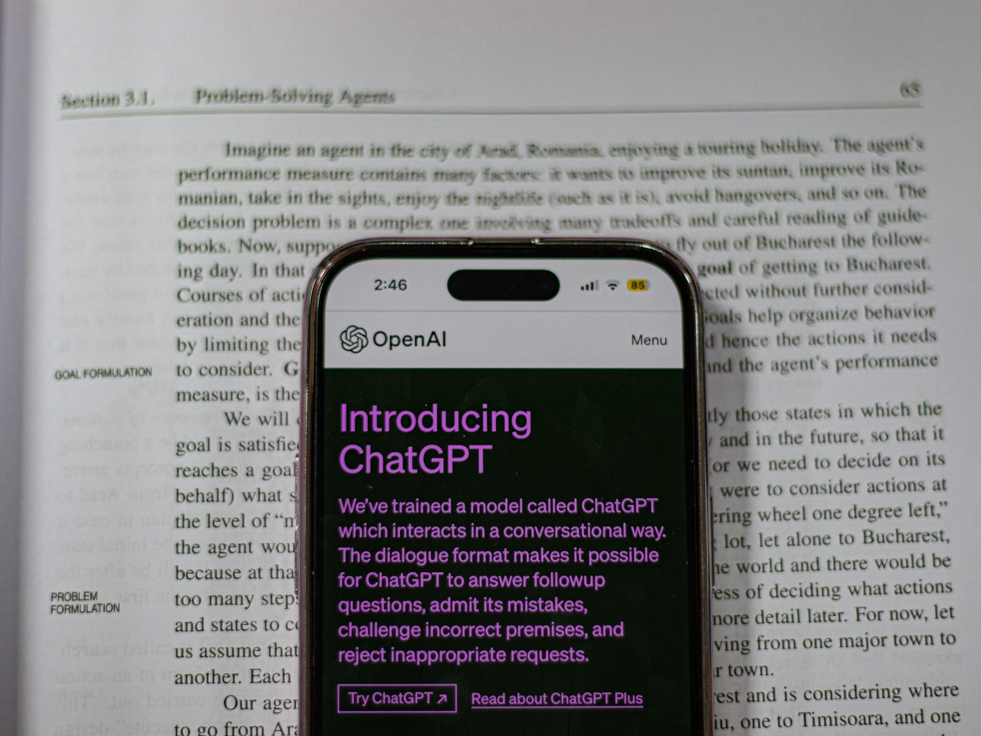 Smartphone showing OpenAI ChatGPT in focus, on top of an open book, highlighting technology and learning.