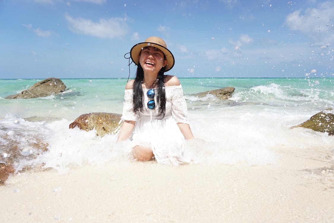 Woman Sitting On Shore In White Off-shoulder Dress