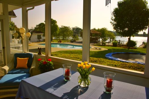 Cozy patio with flowers and candlelit setting overlooking a pool and lake in Stevensville, MD.