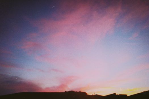 A stunning pink and blue sunset sky with silhouetted mountains, perfect for serene and dreamy settings.