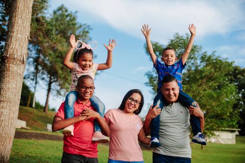 Free A joyful family spending quality time outdoors with kids on parents' shoulders. Stock Photo
