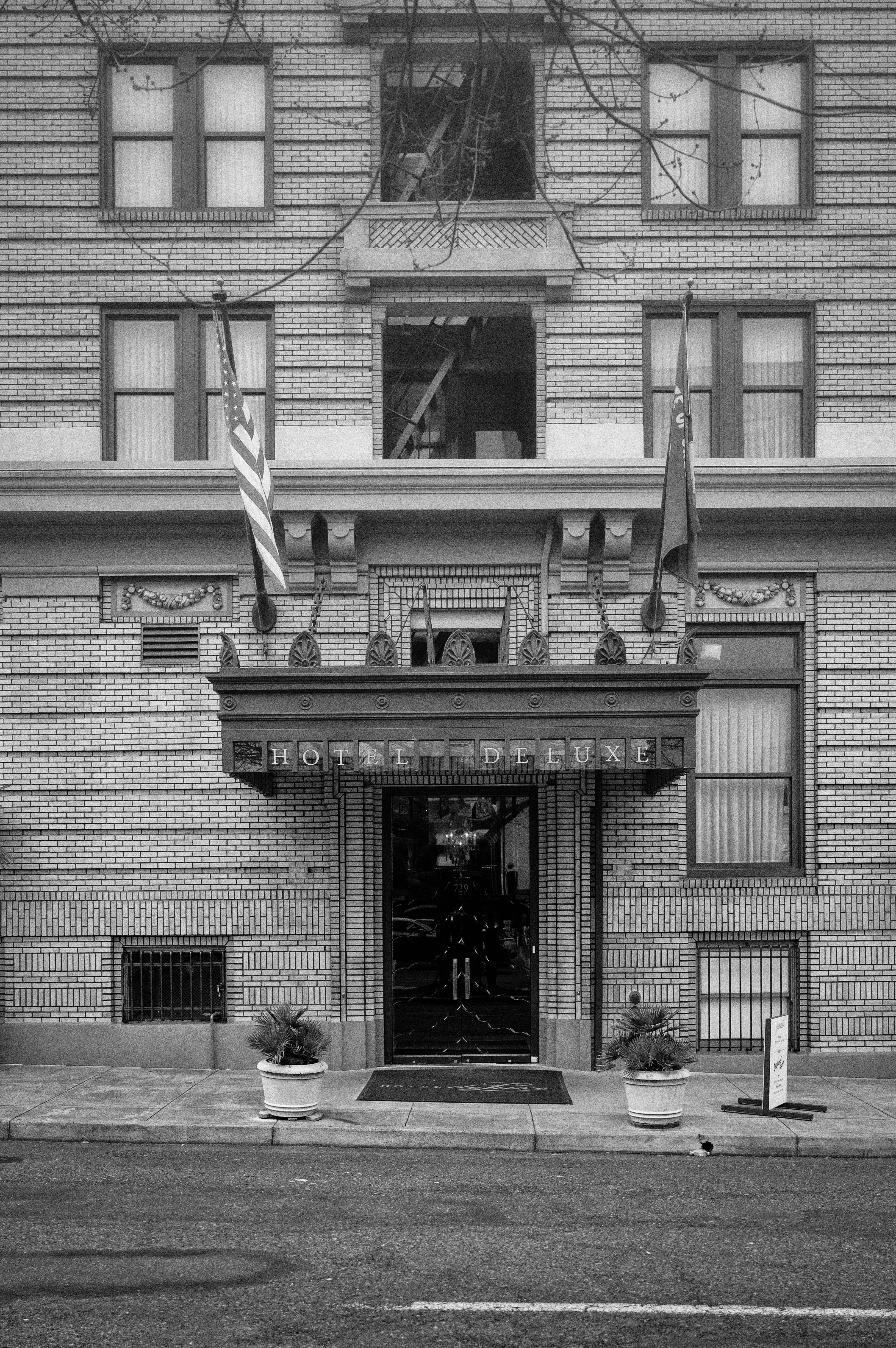 Monochrome image of Hotel DeLuxe entrance in Portland, OR, showcasing classic architecture.