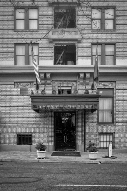 Monochrome image of Hotel DeLuxe entrance in Portland, OR, showcasing classic architecture.