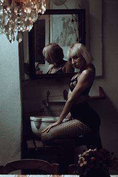 Portrait of a blonde woman posing in black lingerie with a mirror reflection.