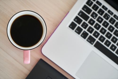 Free Overhead view of a pink coffee mug and laptop on a wooden desk, perfect for productivity. Stock Photo