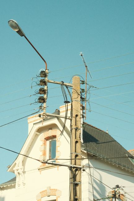 A low angle view of a building facade with power lines and a clear blue sky.