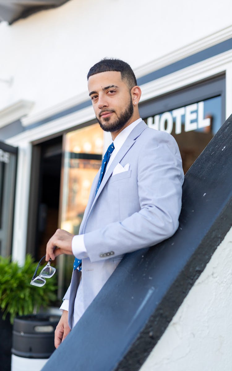 Man In Suit Posing With Eyeglasses In Hand