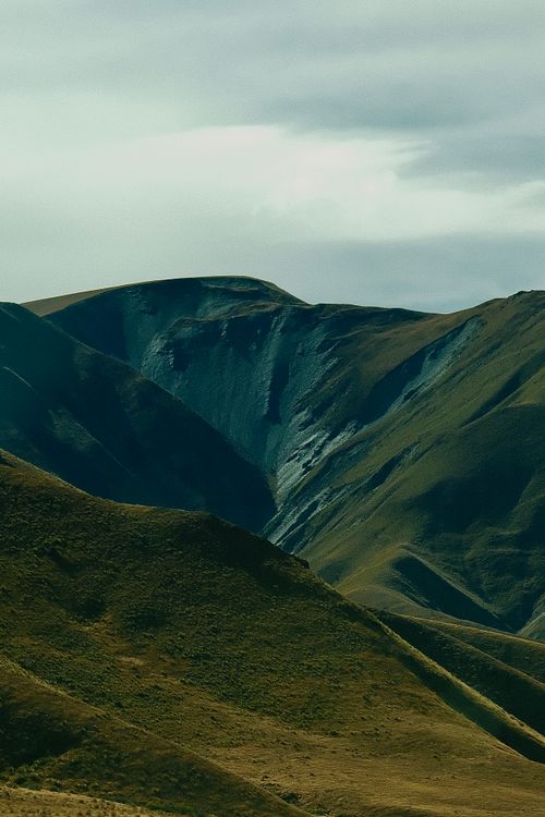 Free A breathtaking view of lush green mountain hills under a cloudy sky, showcasing natural beauty. Stock Photo