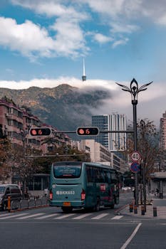 A city street in Seoul featuring a bus and a distant tower under cloudy skies.