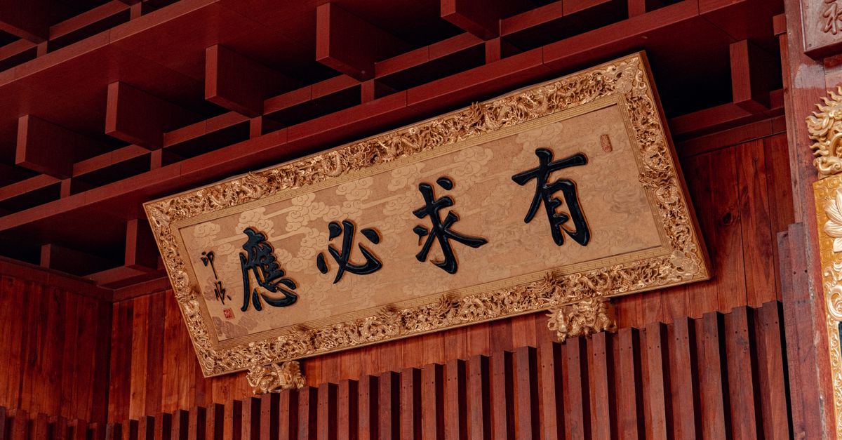 Ornate Chinese sign in a temple setting, featuring golden embellishments and traditional script.