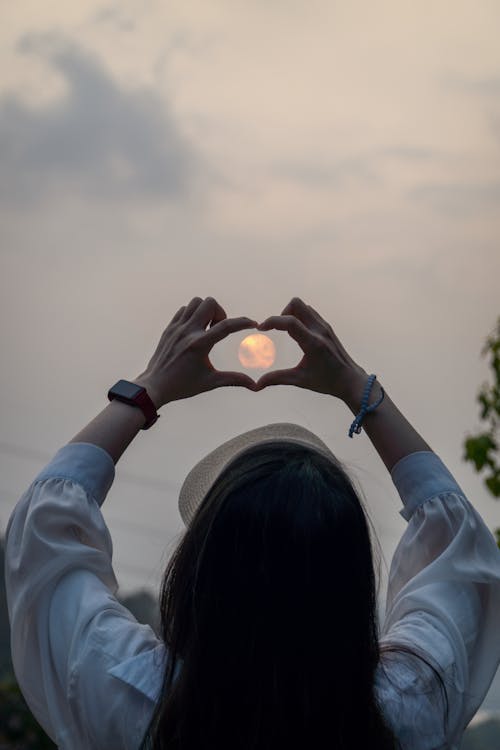 Woman Making Heart Shape with Moon in