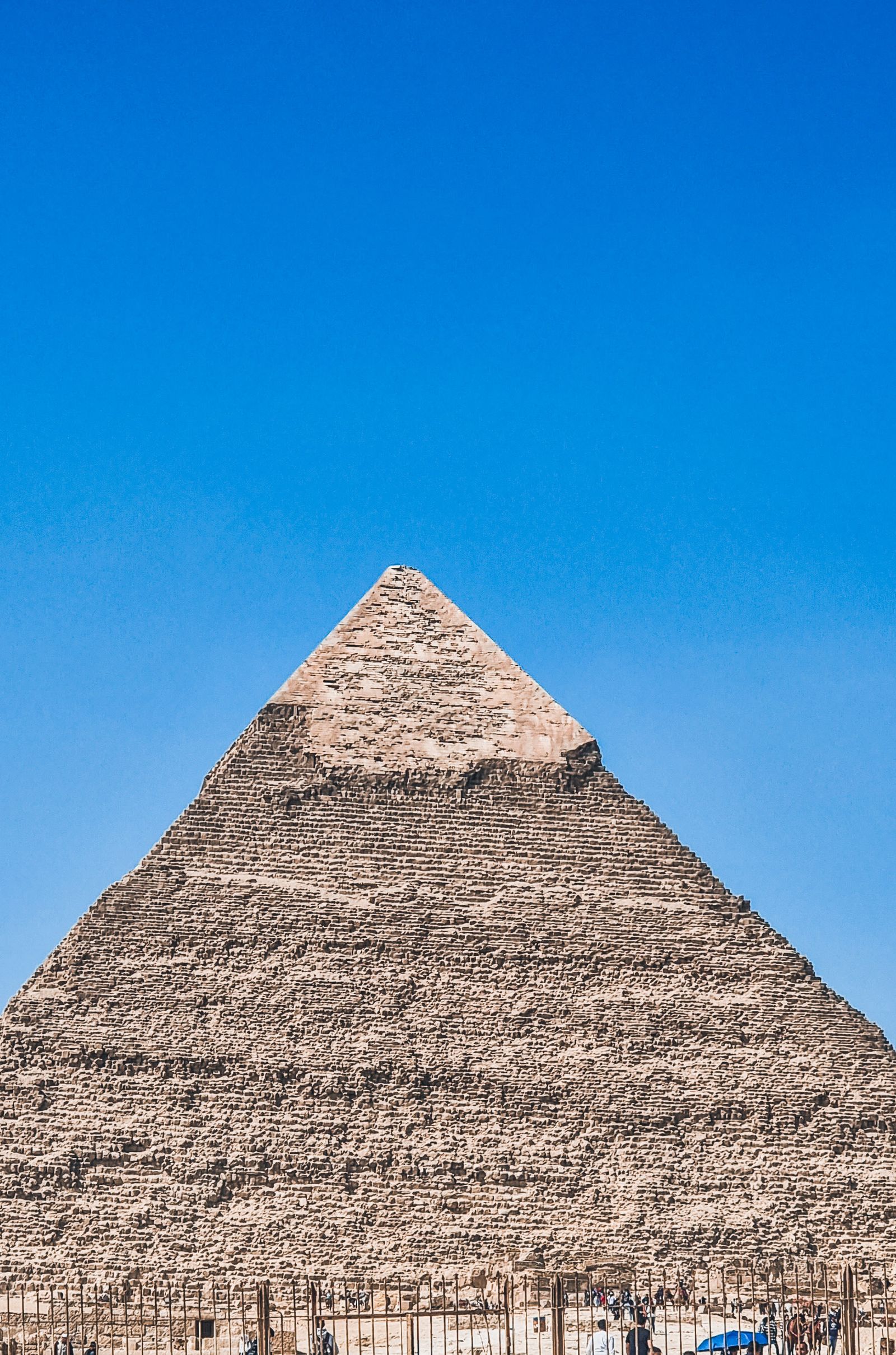 Stunning view of the Pyramid of Giza against a bright blue sky, capturing ancient Egyptian architecture.